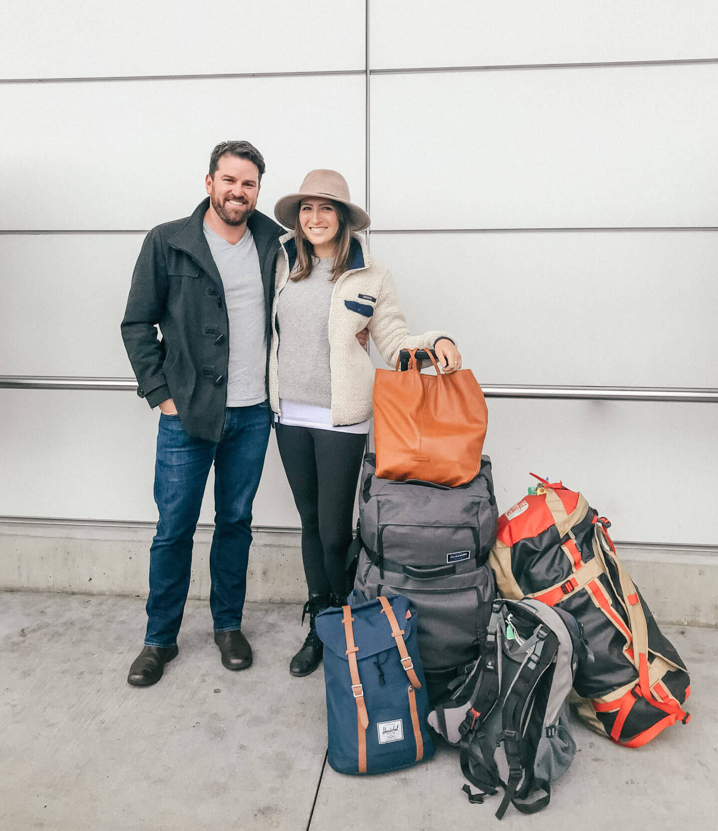 Why I Quit my Dream Job to Travel - A couple smiles at the airport with their luggage before heading off on a two year trip around the world! - the Best Travel Planning Resources & Travel Gear I Swear By