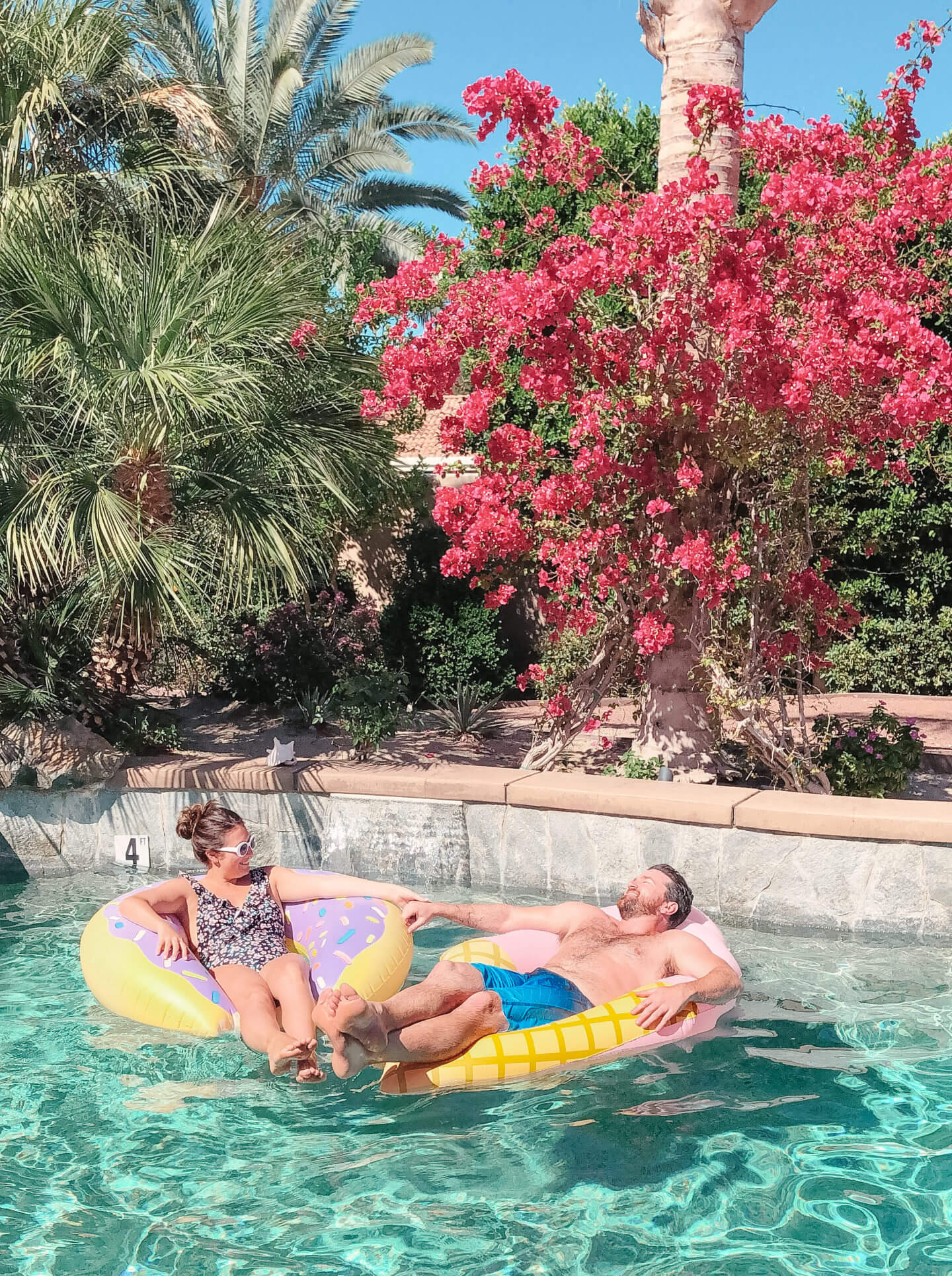 A couple sit in pool floaties soaking up the sunshine in a pool in Palm springs.