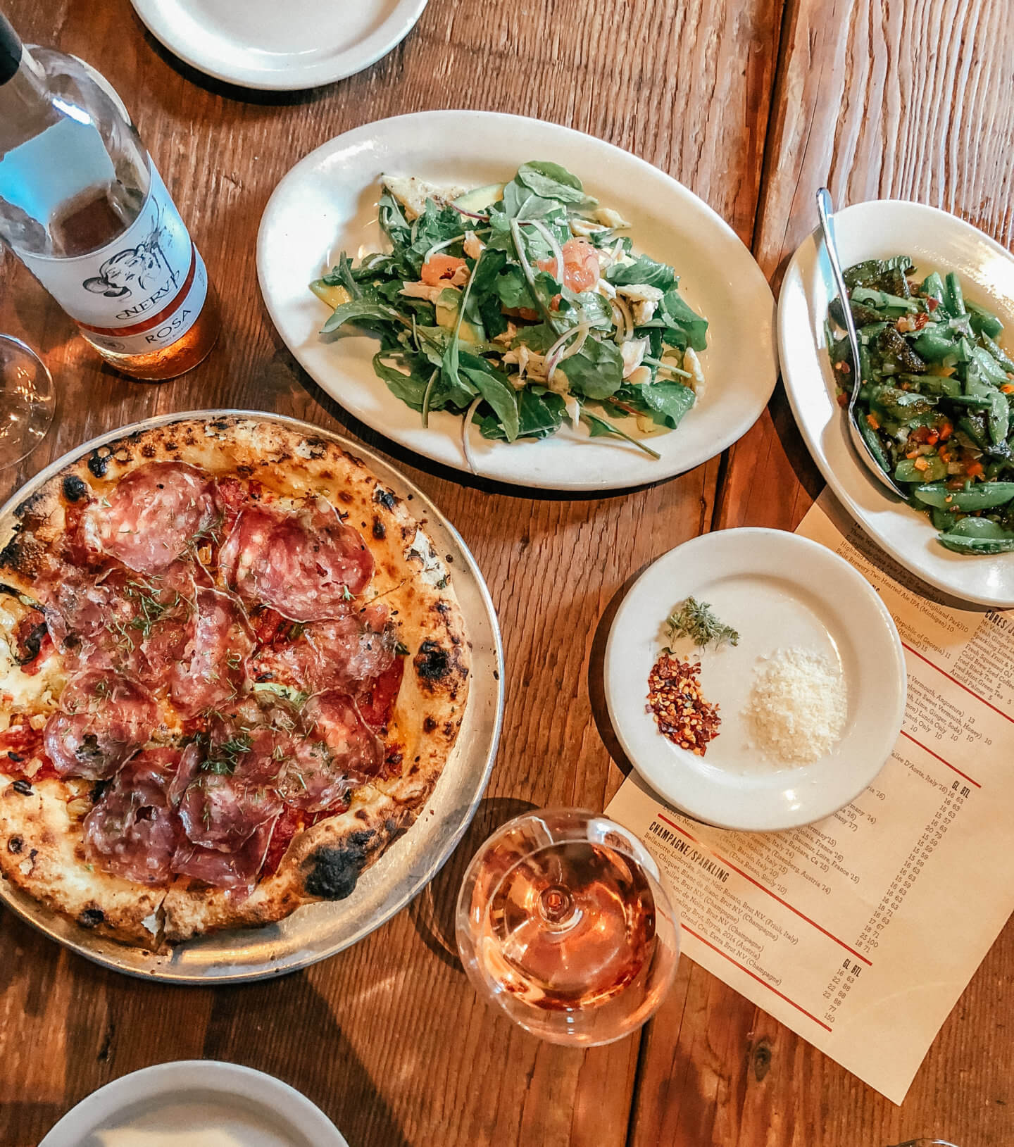 Looking down at a table with pizza salads, and wine in Venice Beach, California