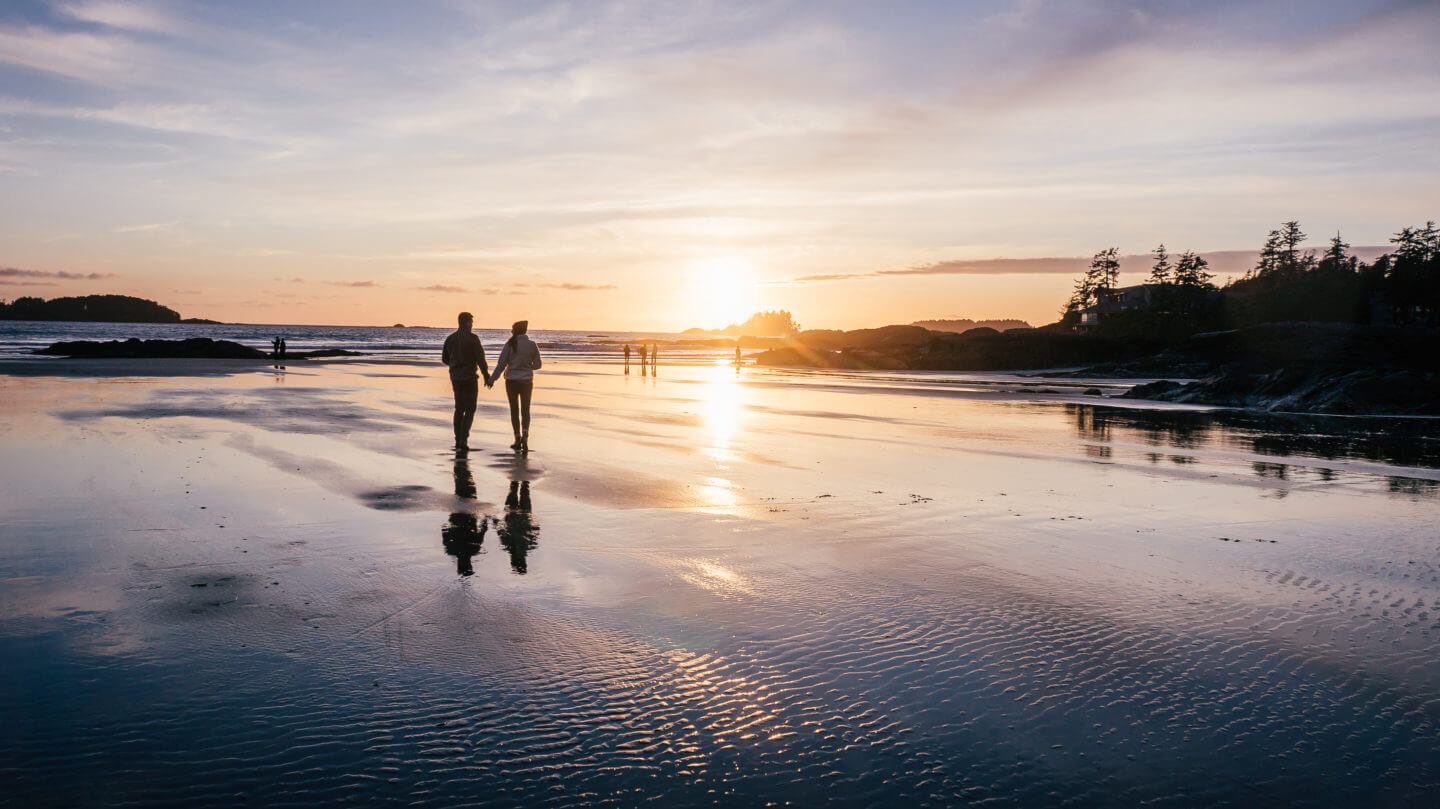 A couple holding hands during sunset in Tofino, BC at Cox Bay