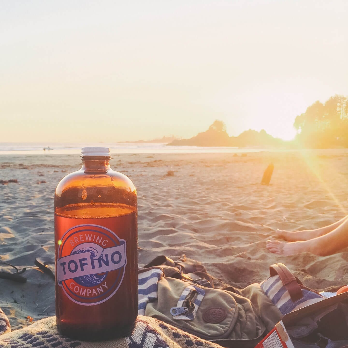 A growler of beer from Tofino Brewing Co. on the beach at sunset 