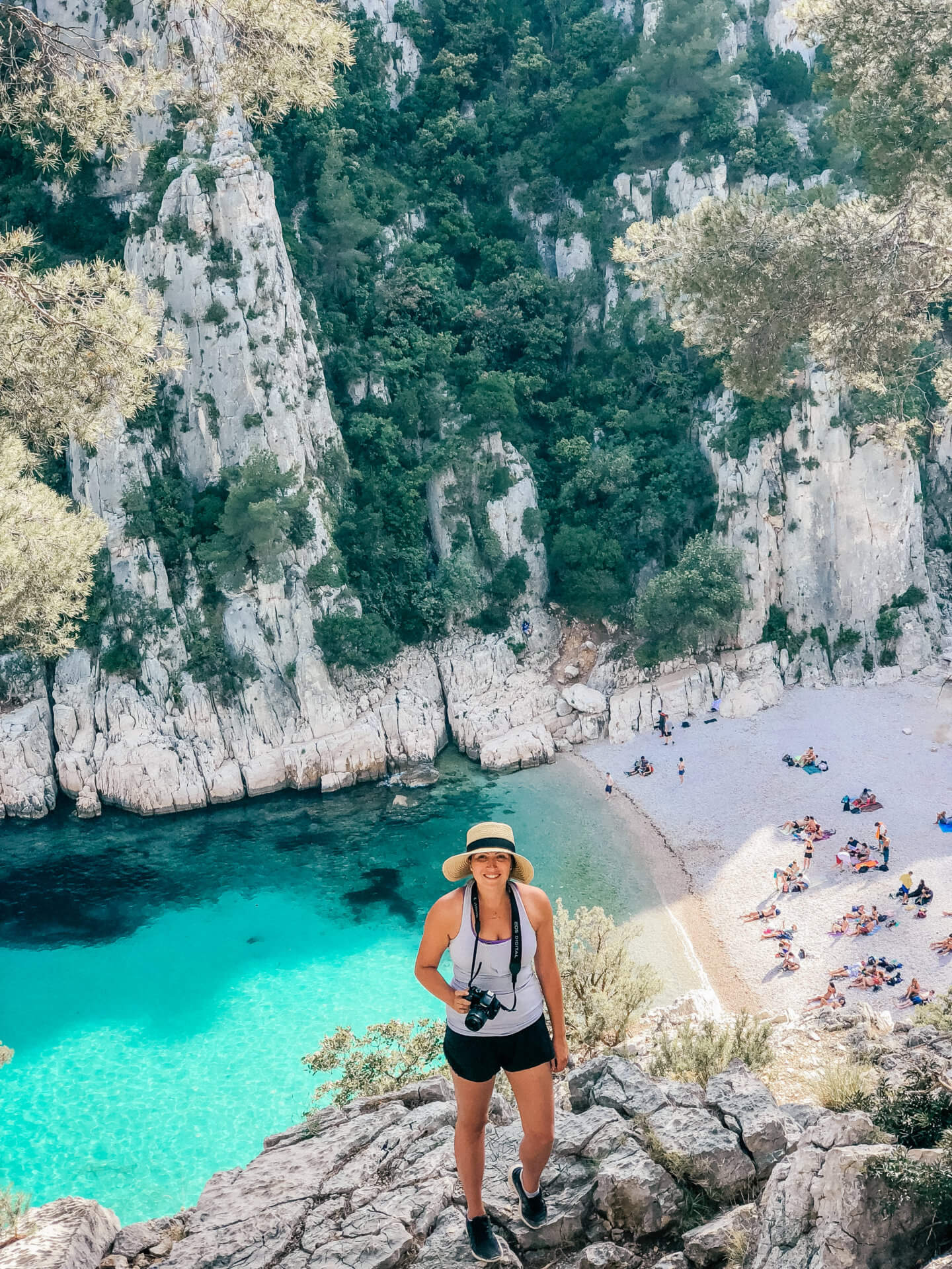Girl wearing a hat and holding her camera hiking in Calanques National Park