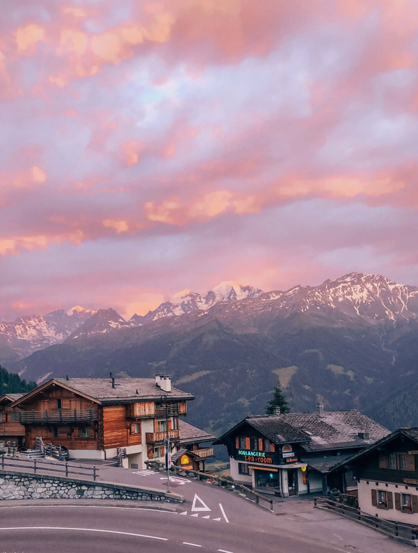 A pink sunset glows over the snowcapped French the Alps during hiking the Tour du Mont Blanc