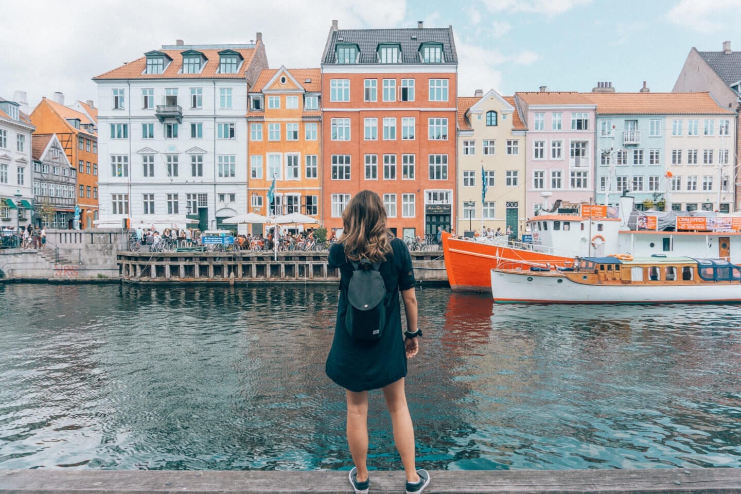 Girl looking at a boat and colourful buildings in Nyhavn in Copenhagen