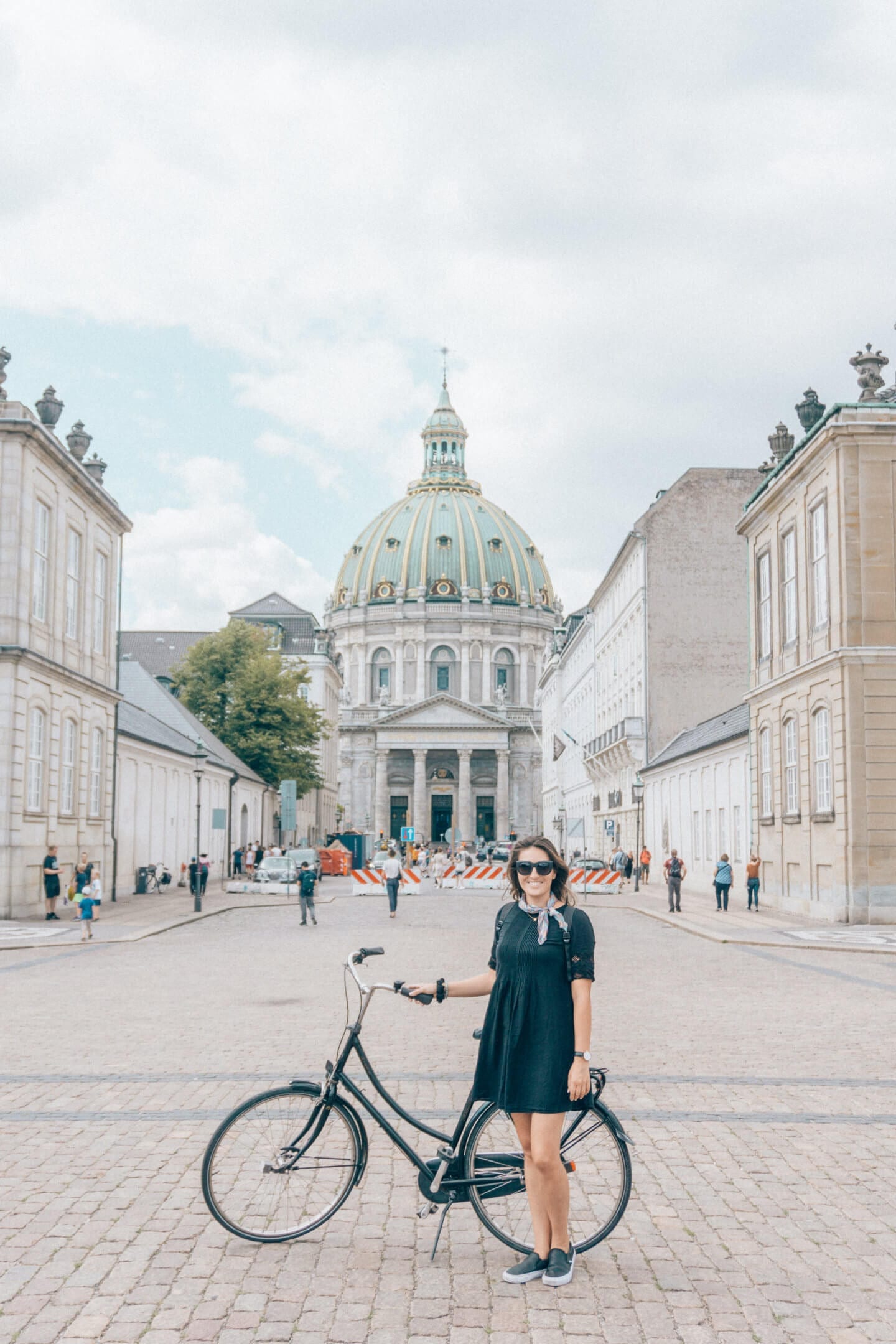 A Girl biking around Copenhagen in front of the domed church