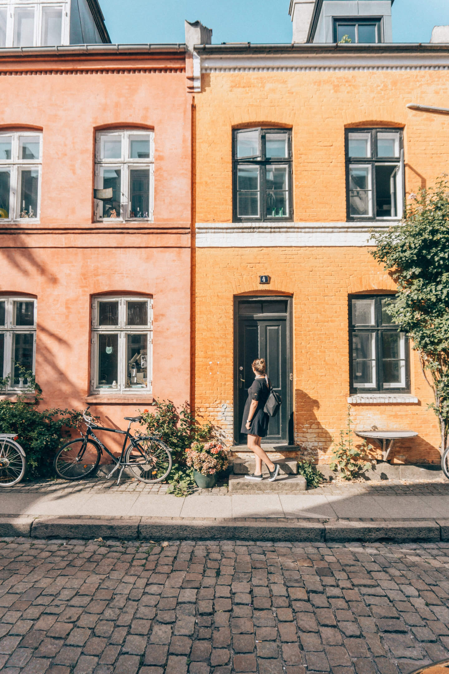 A girl in Copenhagen wanders down a colourful street looking at the traditional apartment buildings in the summer months.