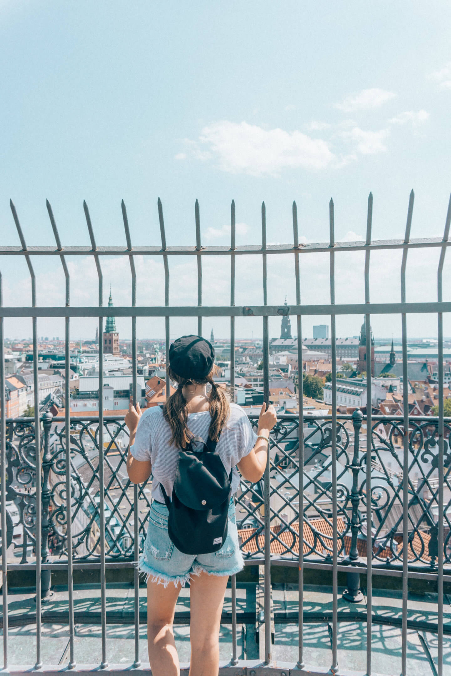 A girl with a hat and backpack at the top of the astronomy tower in Copenhagen