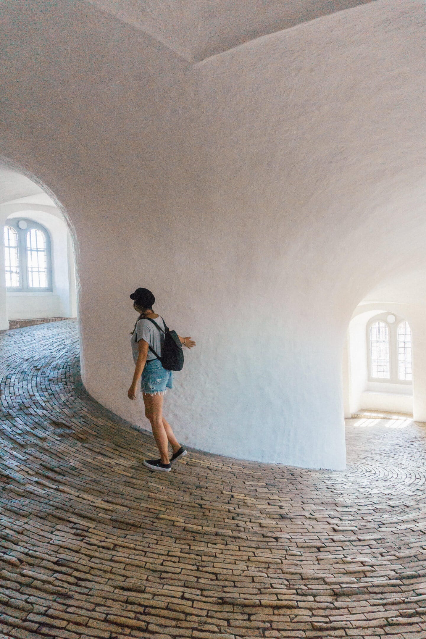 A girl with a hat and backpack climbing up the astronomy tower in Copenhagen