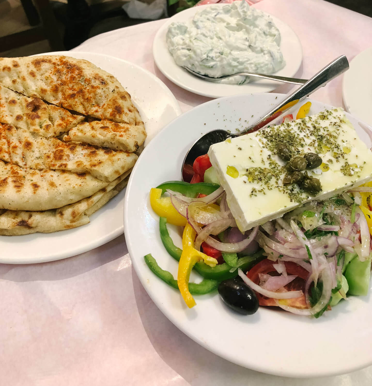Your 10 days in Greece itinerary will allow you to try lots of Greek food like this table full of Greek salad, pita bread and tzatziki 