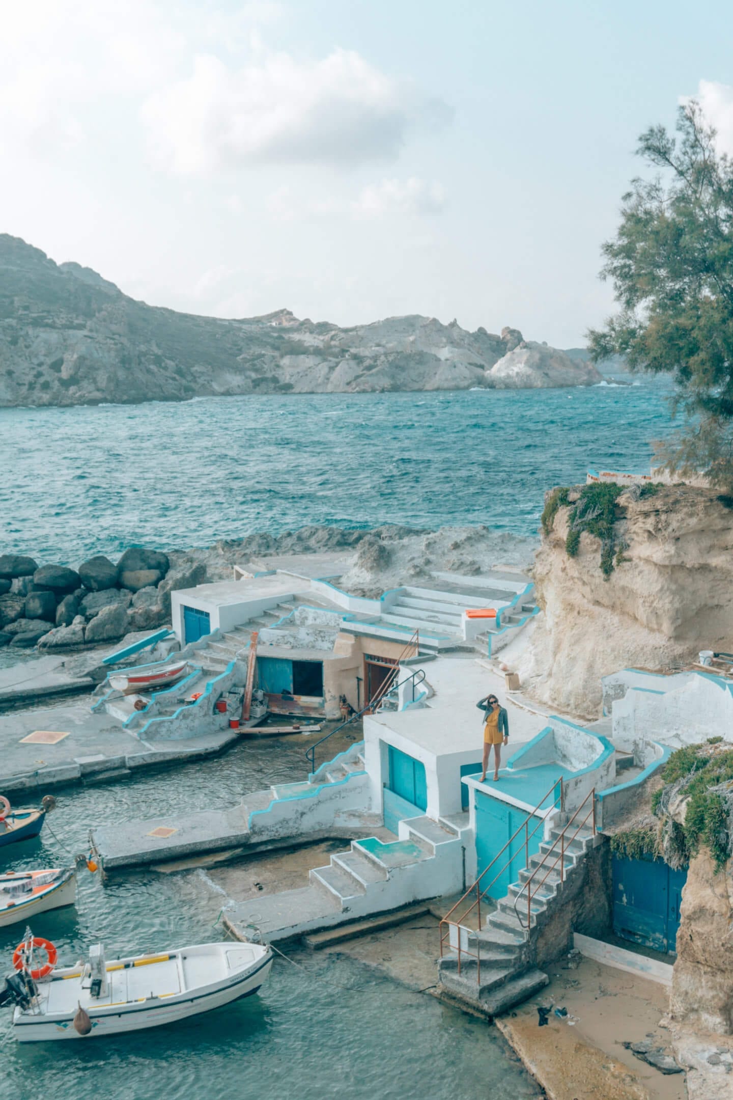 Girl standing on top of Colourful house in fishing village - Milos travel guide