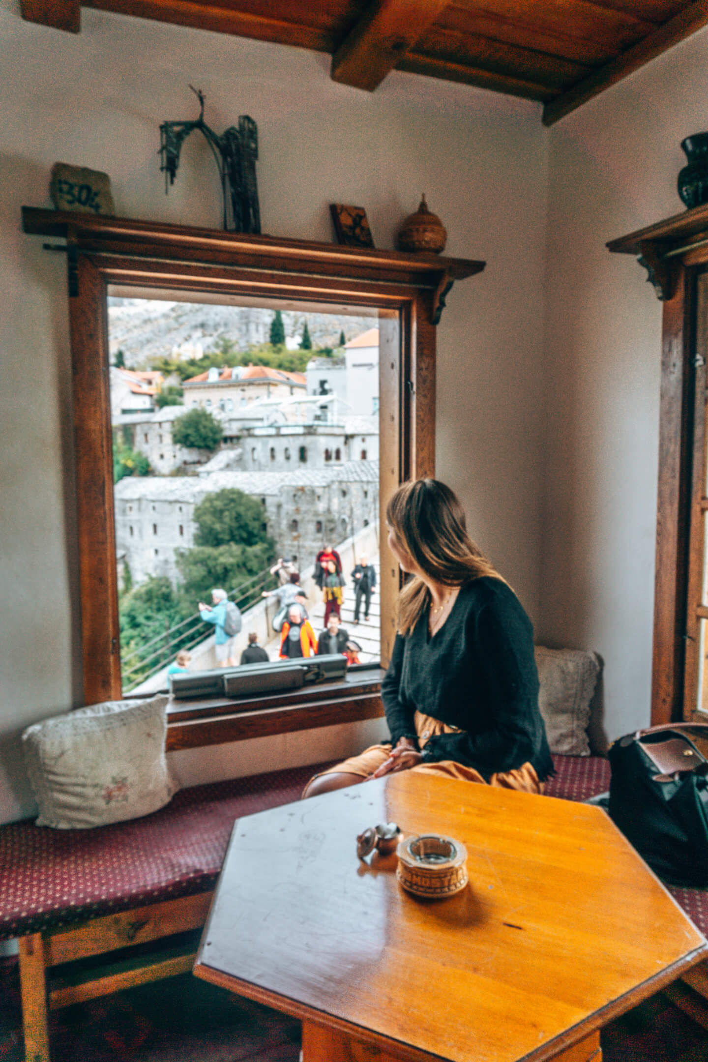 Brunette girl looking out a window to the old mostar bridge