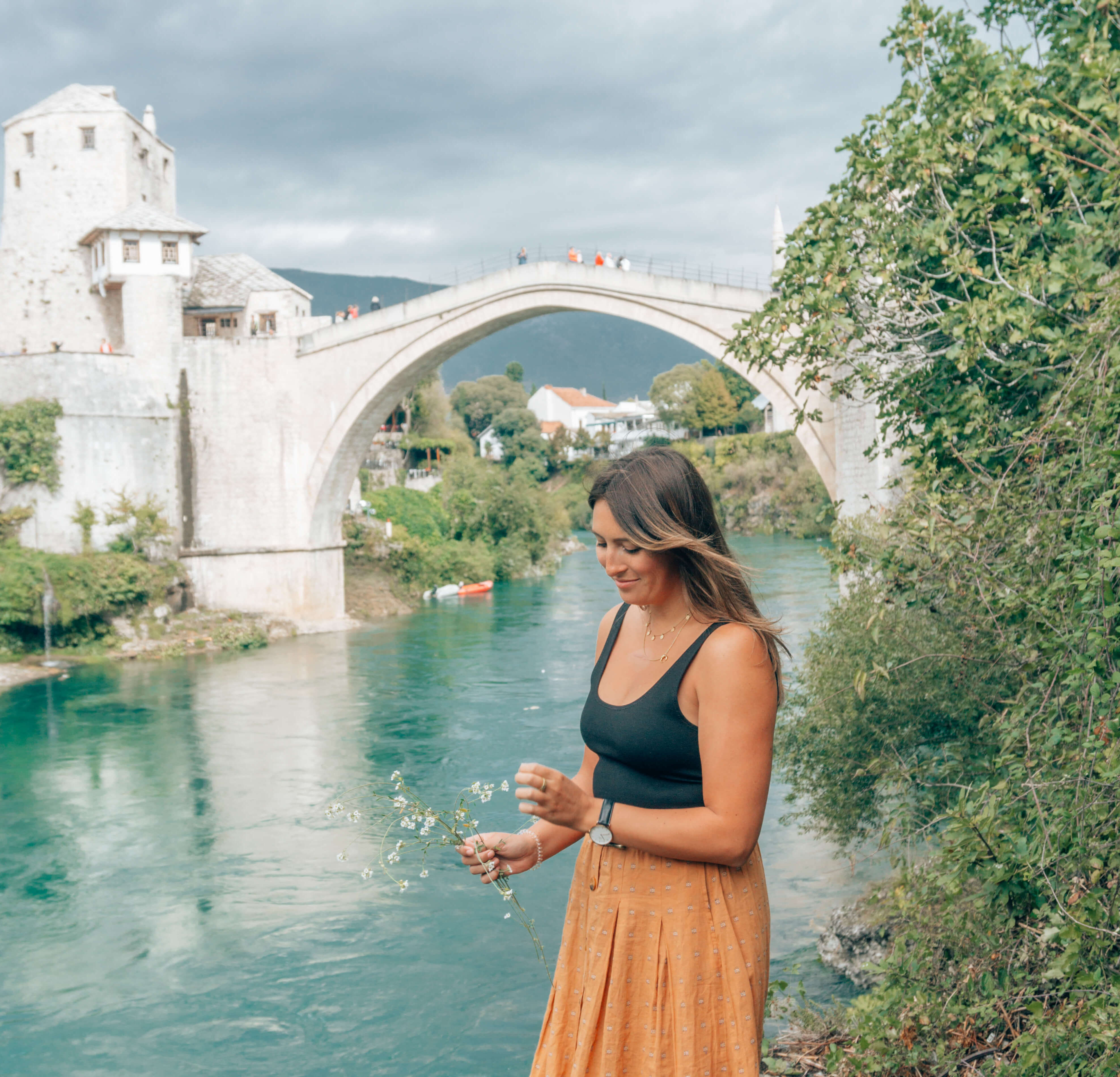 Girl picking flowers in front of Stari Most Bridge - Mostar
