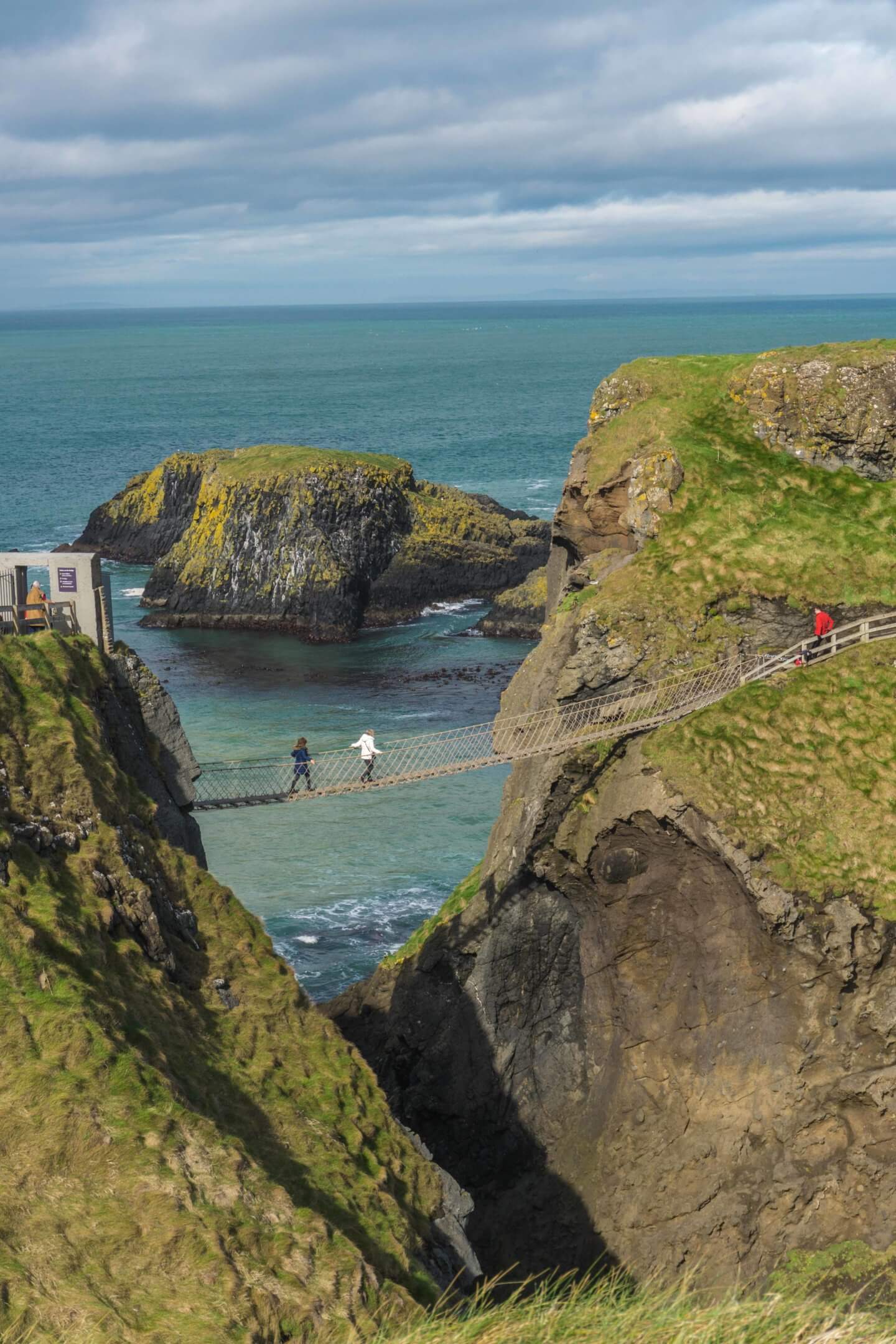 Two people crossing the National Trust Carrick-a-Rede Rope Bridge