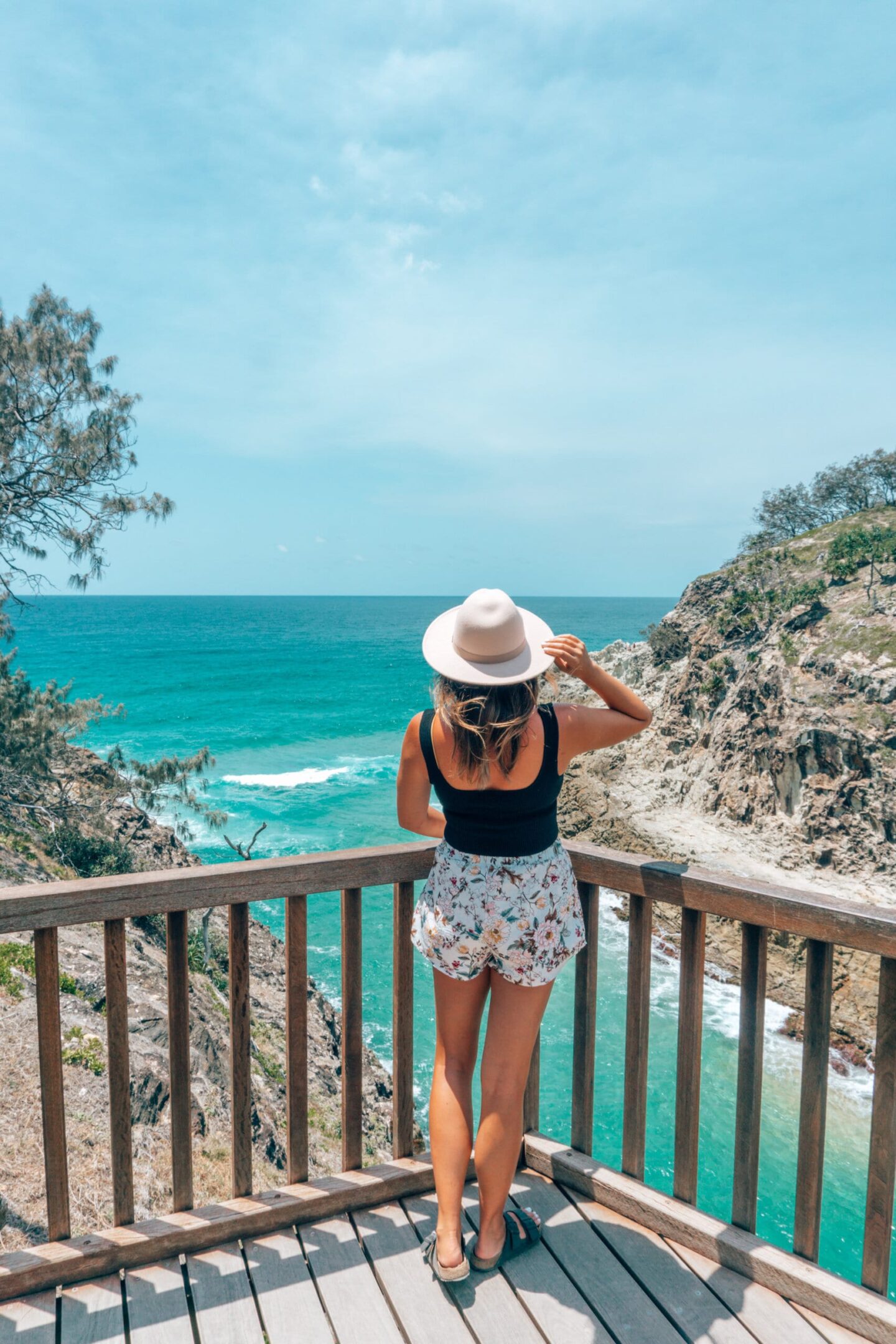 Girl with a hat on looks out at the ocean on down a stairs on the Stradbroke Gorge walk 