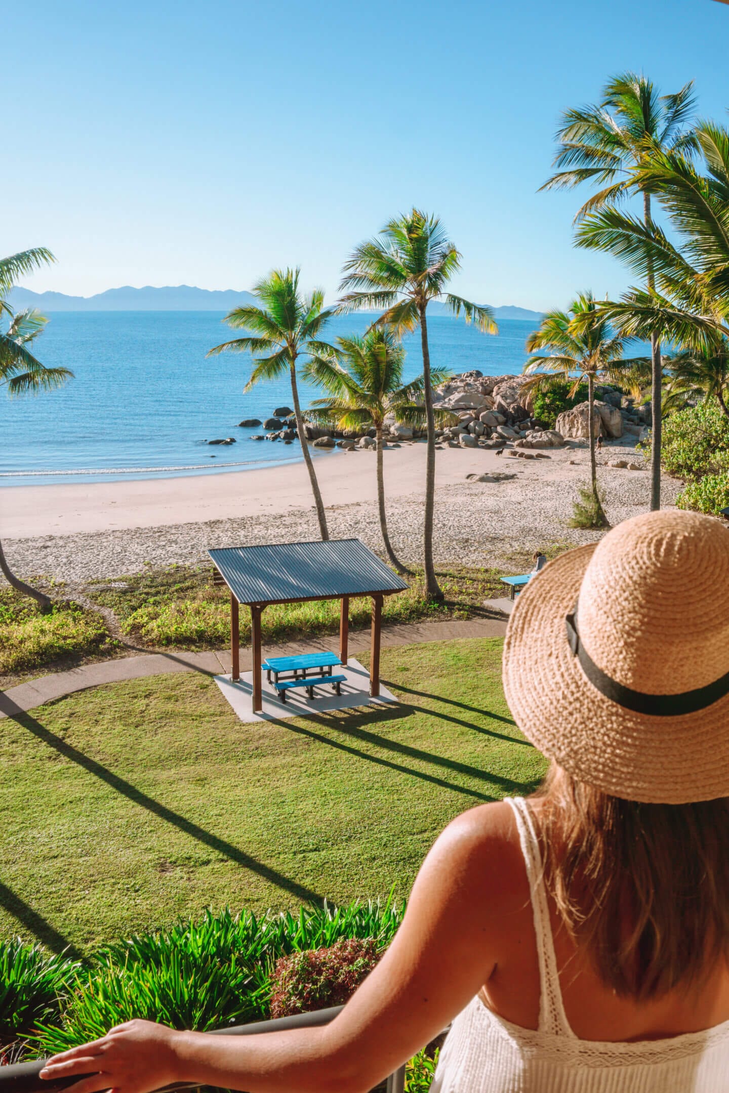 A girl wearing a hat looking out at the view from her hotel room at the Rose Bay Resort