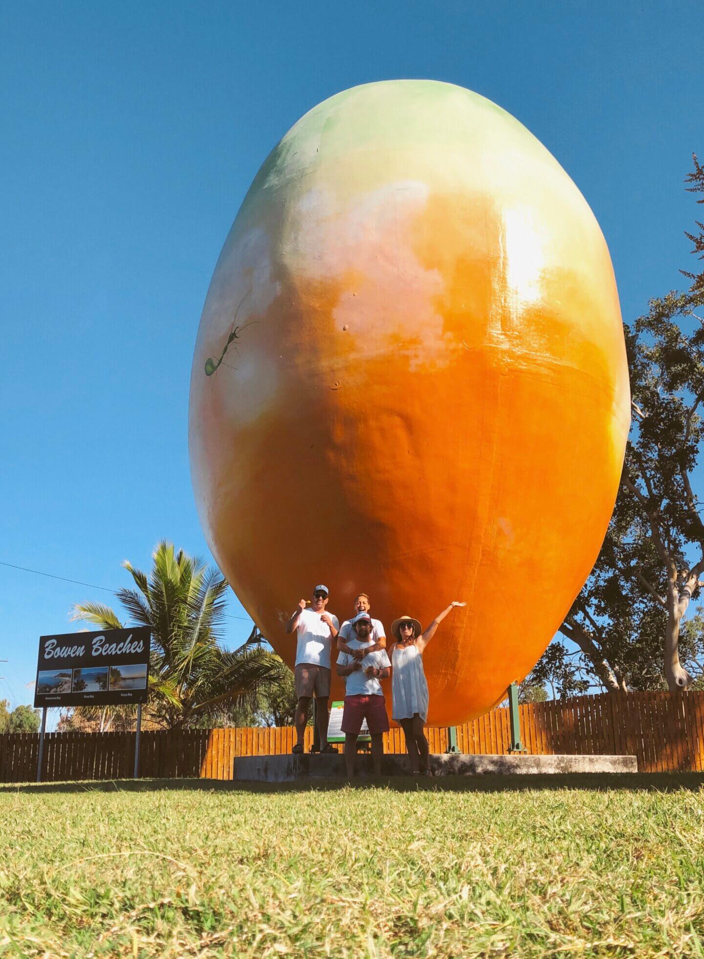 Four friends standing in front of the big mango statue in Bowen queensland