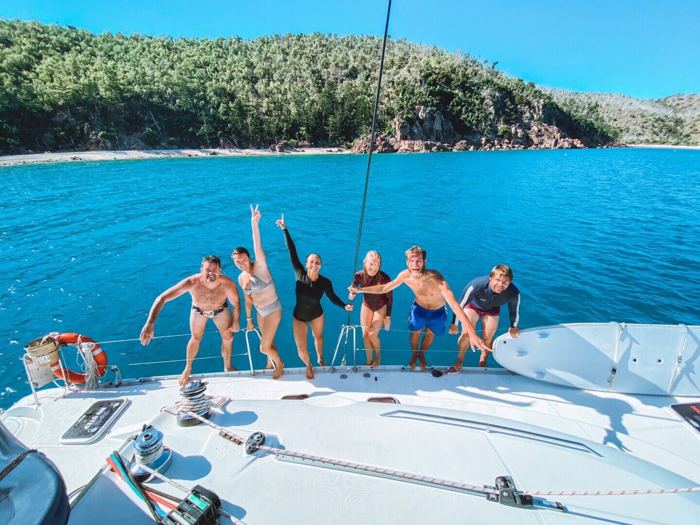 A group of friends on a sailboat in the Whitsundays about to jump off