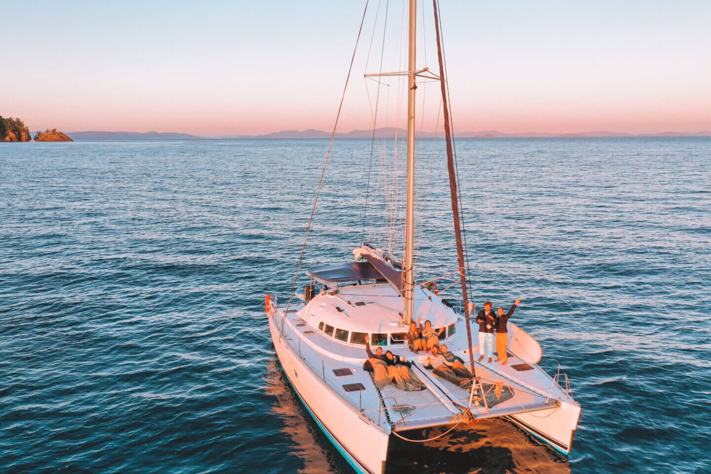 Looking down at a sailing boat with people on it watching sunrise