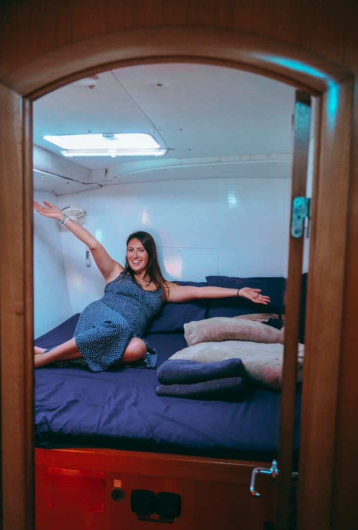 Girl sitting on a bed in her private bedroom while sailing the Whitsundays