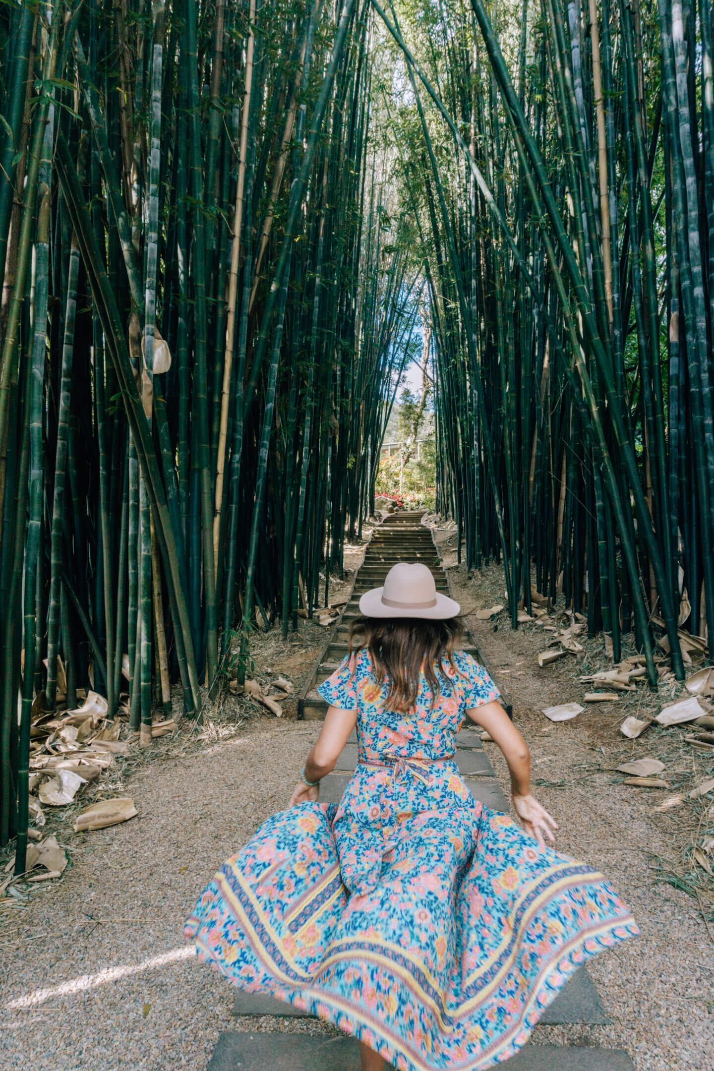Girl in a hat wearing a blue dress running into a bamboo forest at Crystal Castle