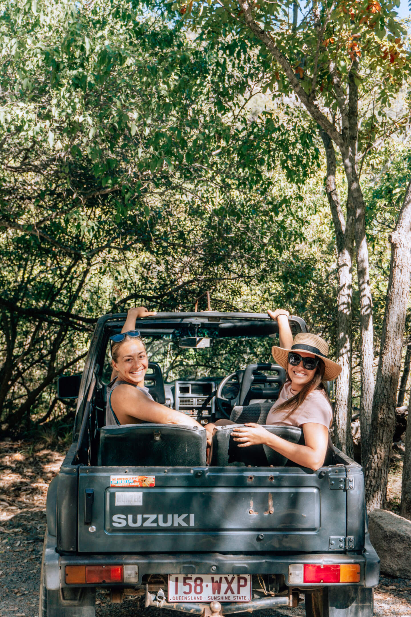 Two girls sit in the back seat of an old topless car on Magnetic Island