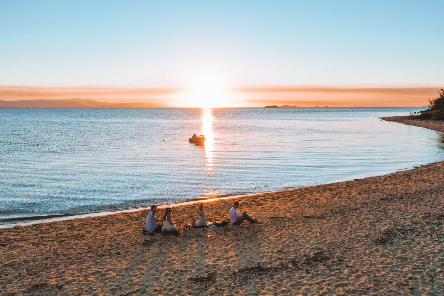 Four friends sitting on West Point beach for sunset on Magnetic island