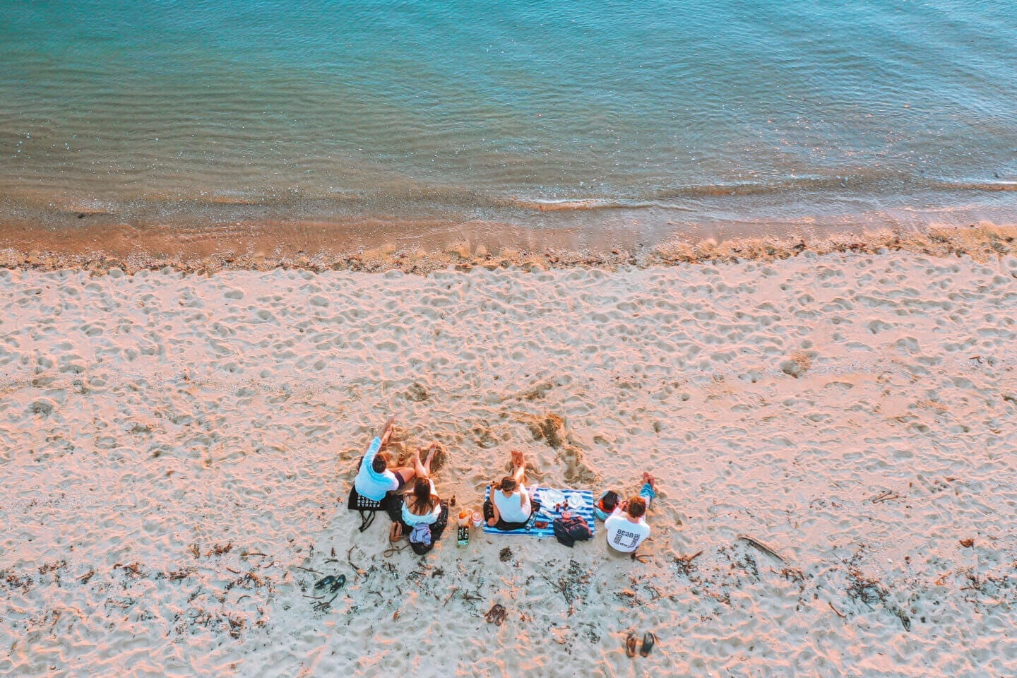 Looking down at four friends sitting on West Point beach for sunset on Magnetic island