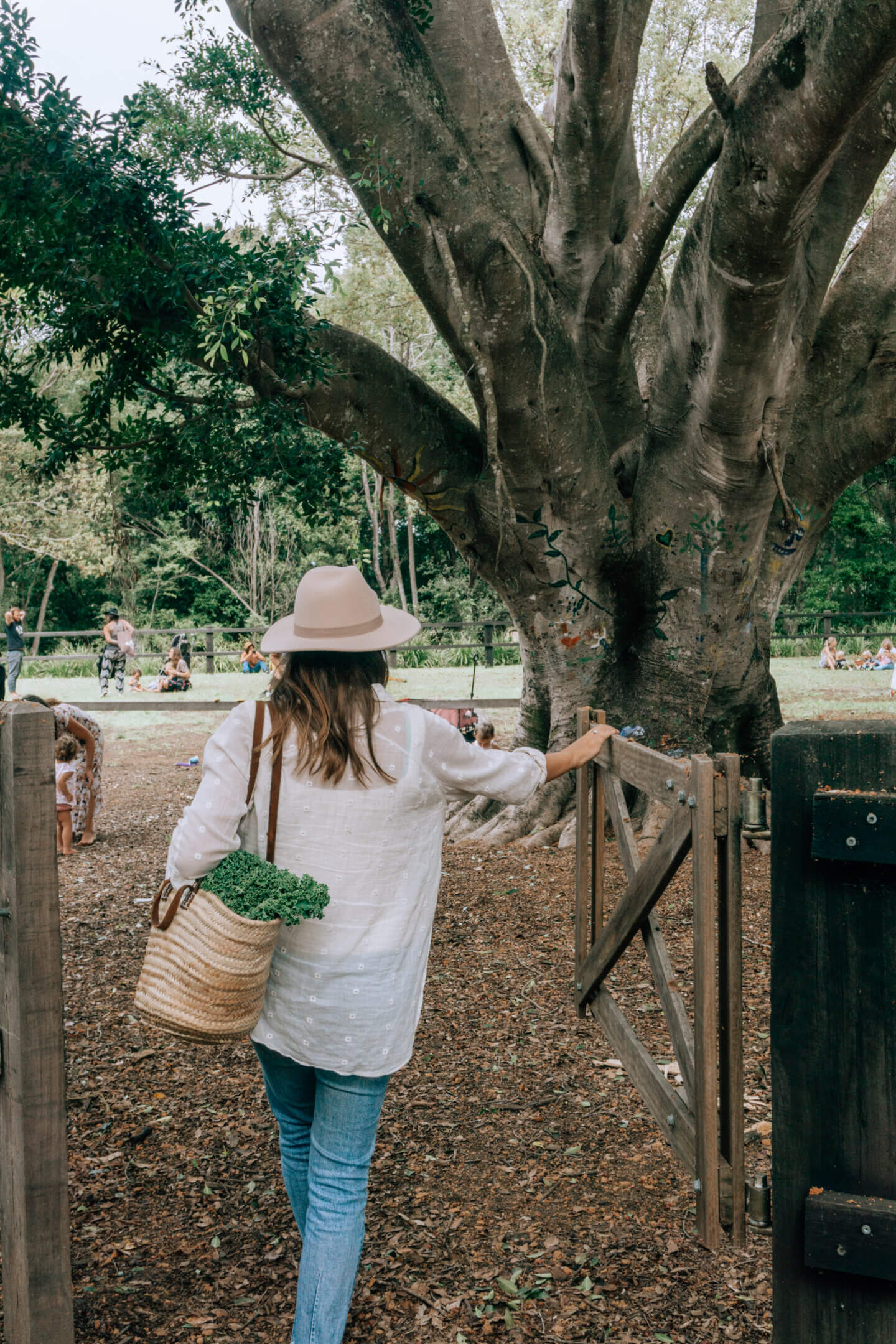 A girl with a hat on and a wicker bag walks into the Mullumbimby Farmers Market 