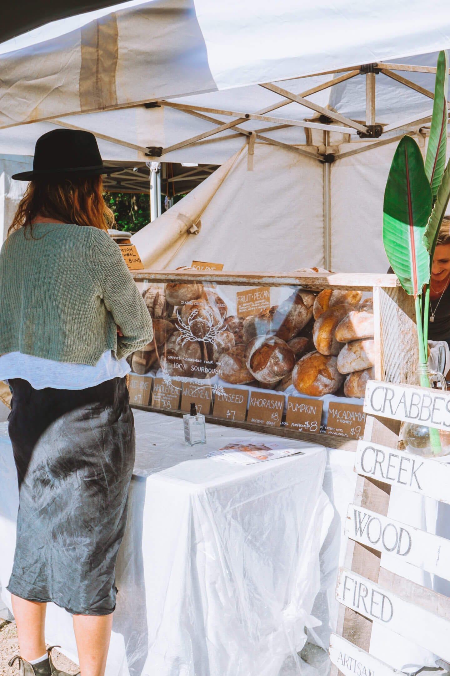 A girl wearing a black hat waits to buy fresh bread at the Mullumbimby Farmer's market