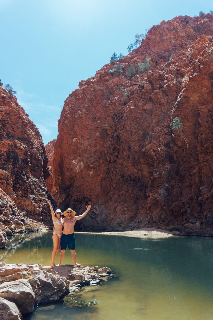 An excited women and man have their hands up at Redback Gorge in West Macdonnell Ranges on a Alice Springs to Uluru road trip