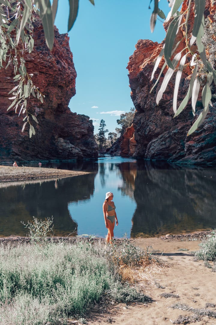 Girl in a green bikini standing in front of Ellery Creek Big Hole in West Macdonnell Ranges