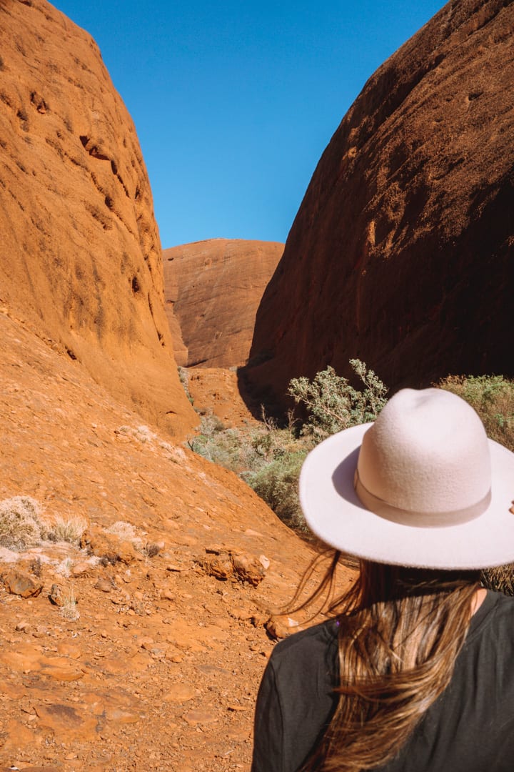 Girl with a hat on looks at the Valley of the Winds at Kata Tjuta