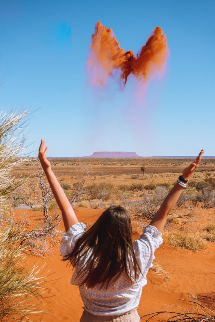 In between Alice Springs and Uluru is Mount Conner - Girl throws red dirt up above Mount Conner