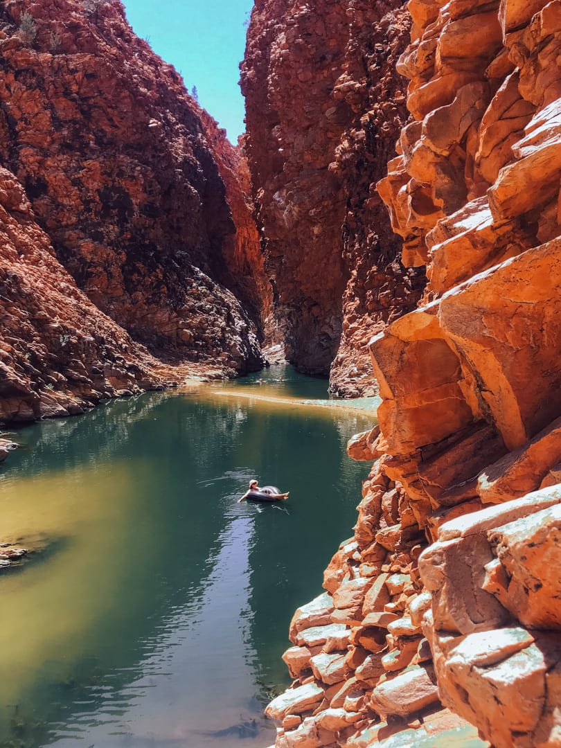 A girl floats on a tube in the middle of Redback Gorge in West Macdonnell Ranges 