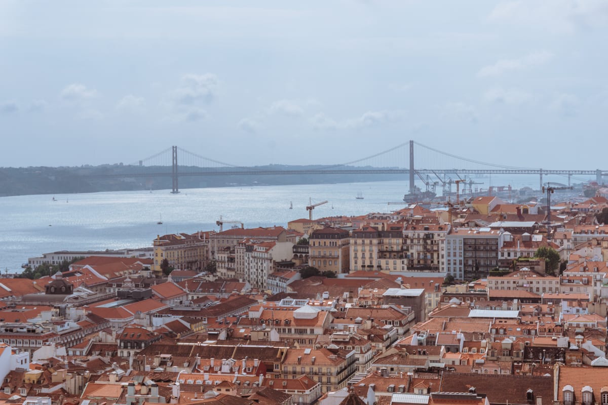 Lisbon's skyline with a sea of terracotta roofs and the bridge in the background. 