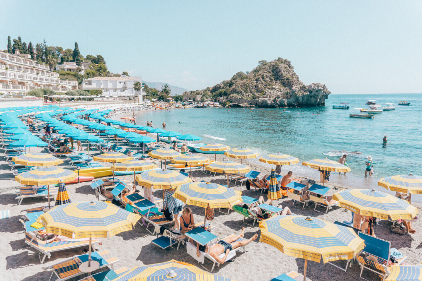 The colourful umbrellas and sunbathers at Taormina beach, a tourist town on Sicily
