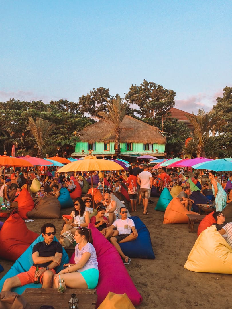 People sitting on colour bean bag chairs under umbrellas in Seminyak, Indonesia