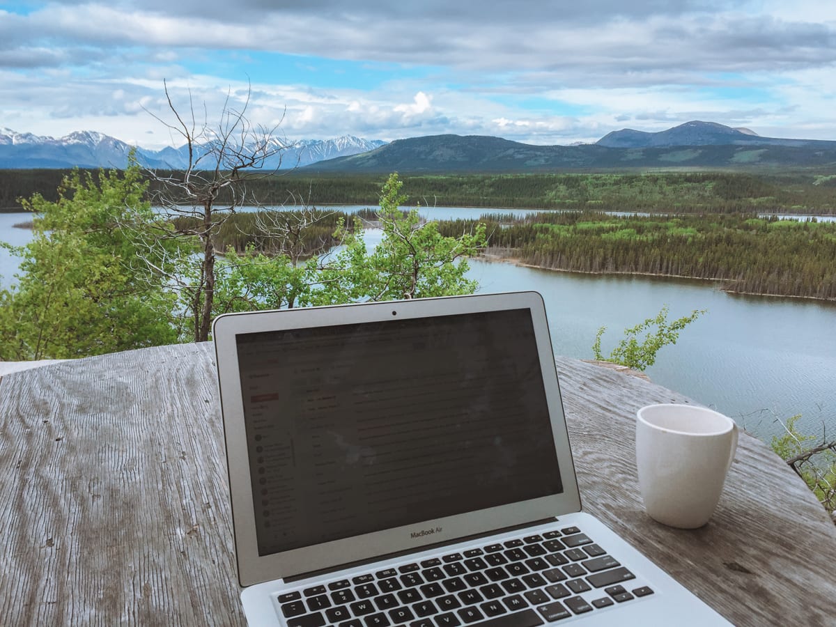 Best places for digital nomads: A laptop on a table with a cup of coffee overlooking the mountain views of Whitehorse, Yukon.