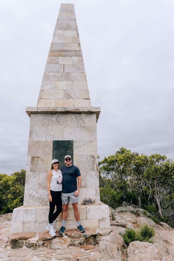 A couple standing in front of the Stamford Hill Flinders obelisk monument in Lincoln National Park