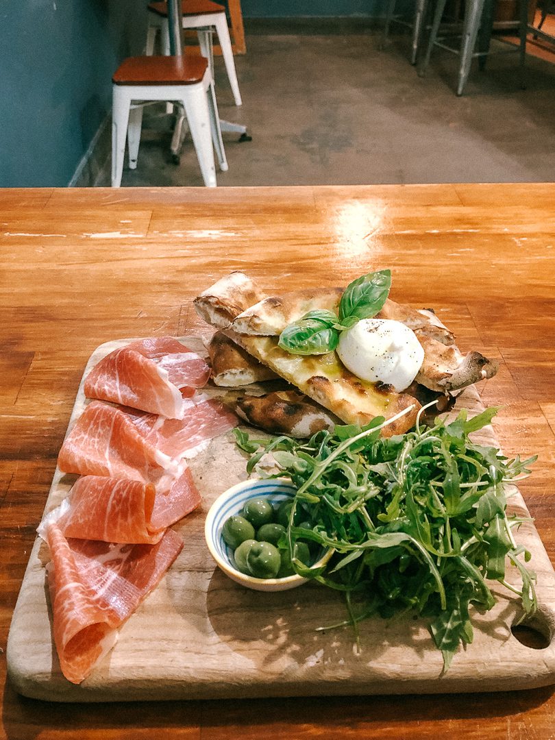 The appetizer plate with burratta, flat bread, green olives, rocket, and prosciutto at Il Buco in Byron Bay