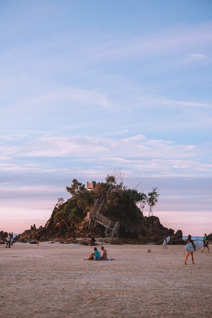 People sitting on the sand during a super low tide at the Pass in Byron Bay, Australia.