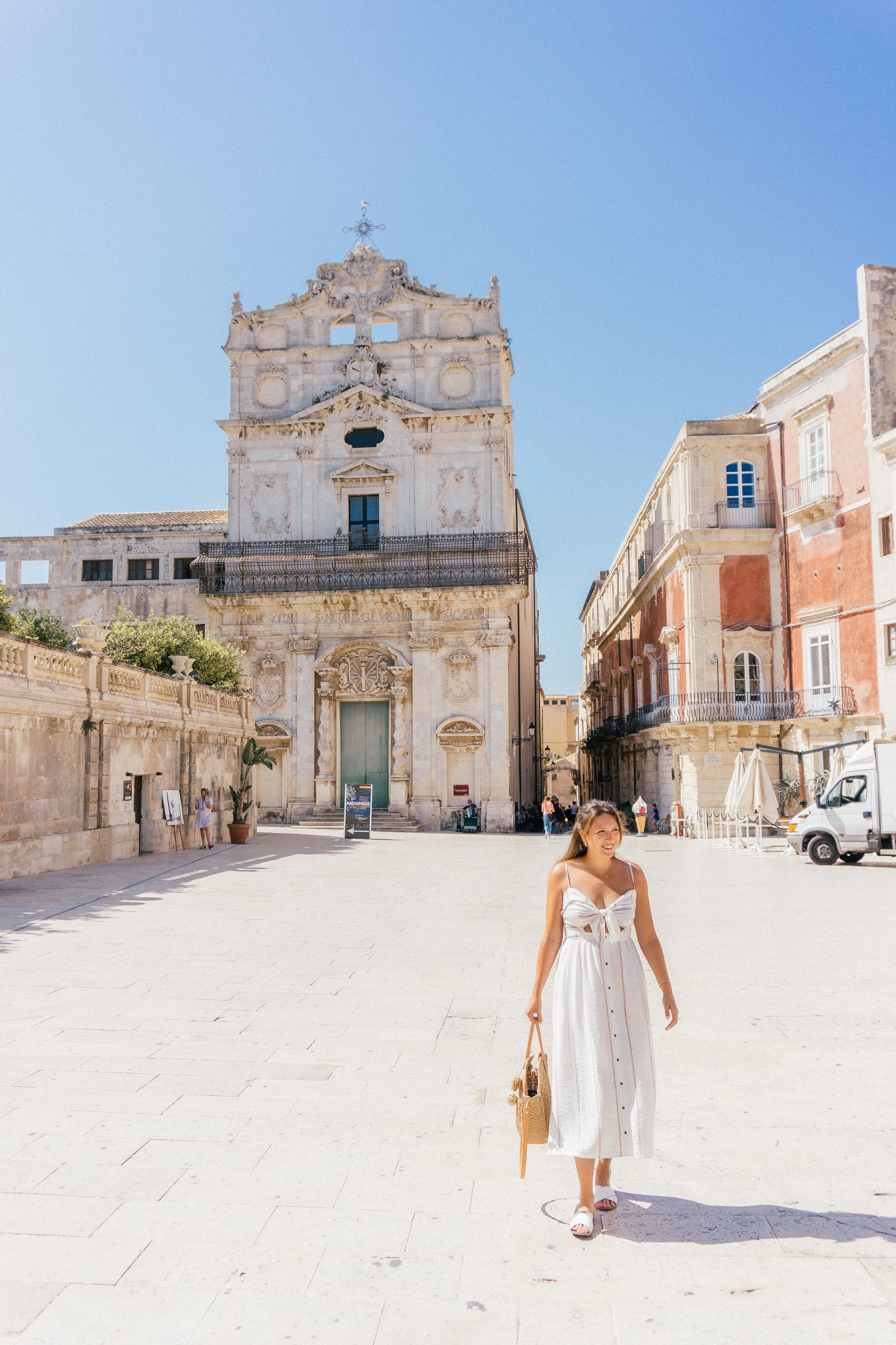 A girl walking through the stunning seaside town of Oritgia - just one of the top stops on this 7-day Sicily Itinerary.
