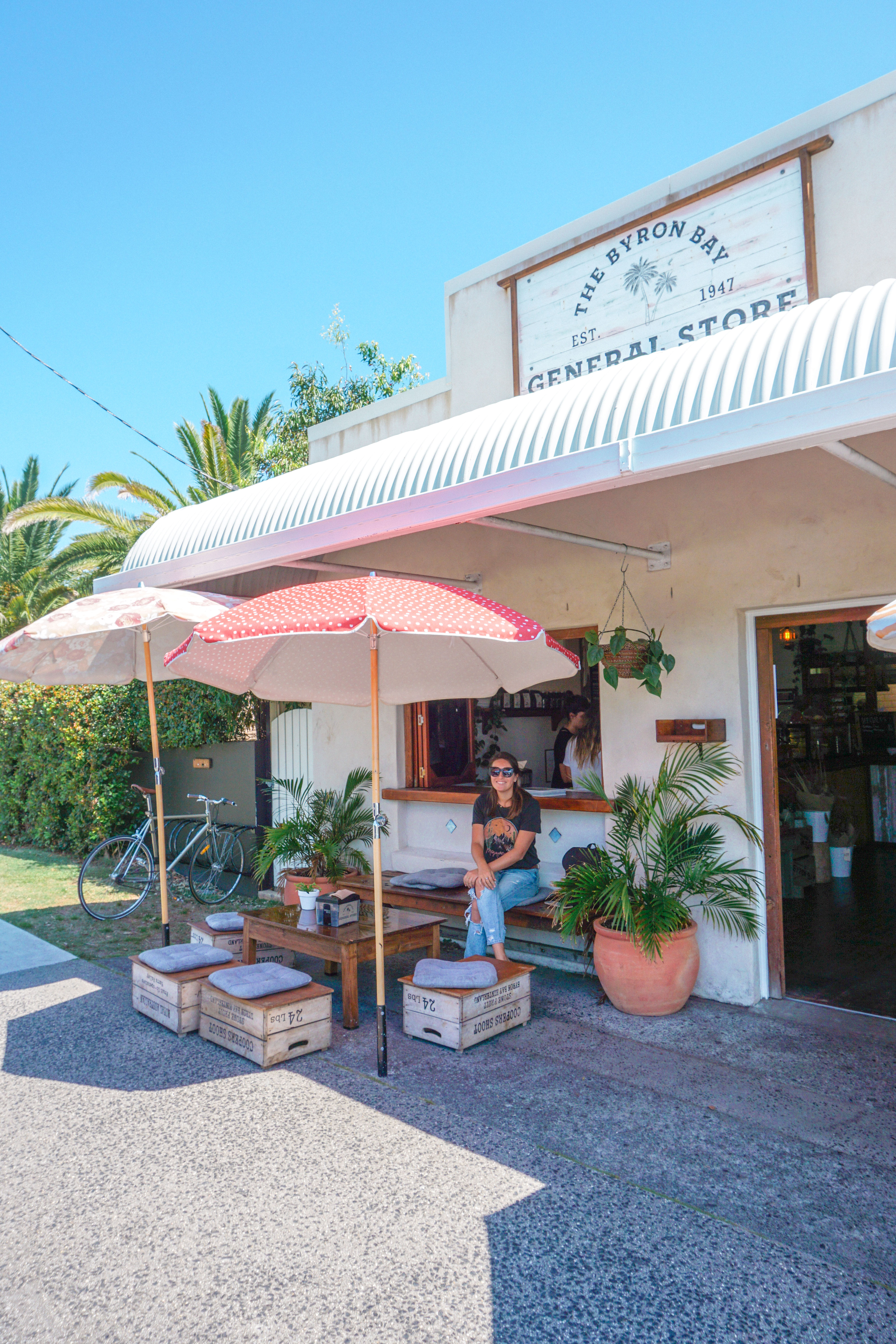 A girl sits on the patio under a beach umbrella at the Byron Bay General Store