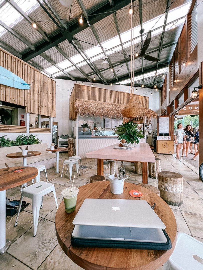 A lap top and smoothie sit on top of a table at Combi Cafe, a trendy spot in Byron Bay, Australia.