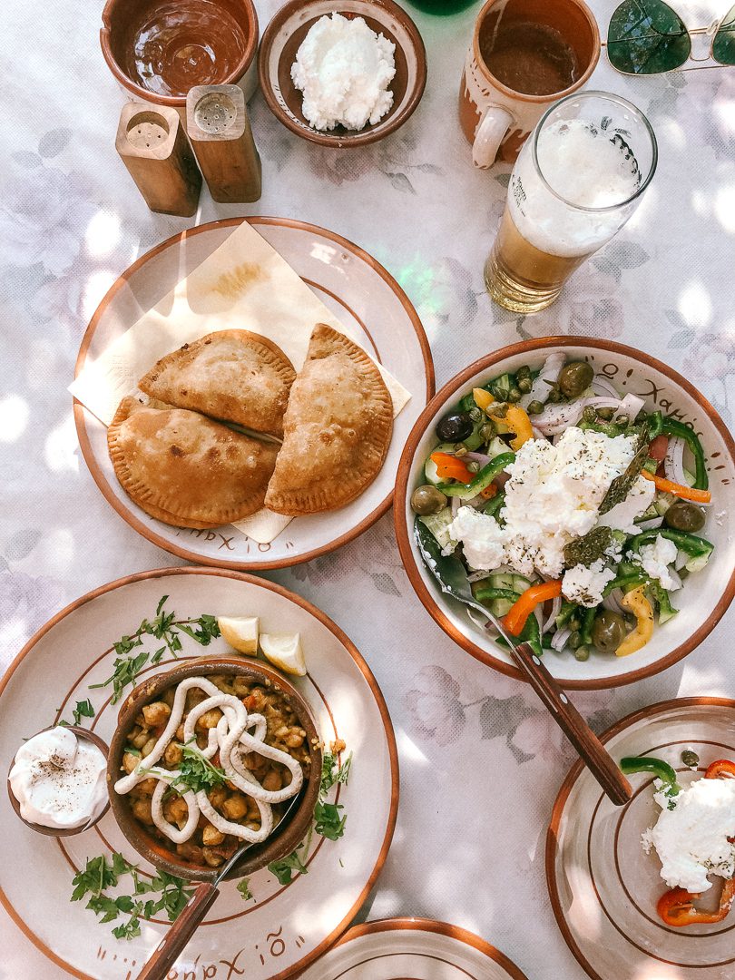 Looking down on a table full of authentic Greek dishes and beer when Greek Island Hopping