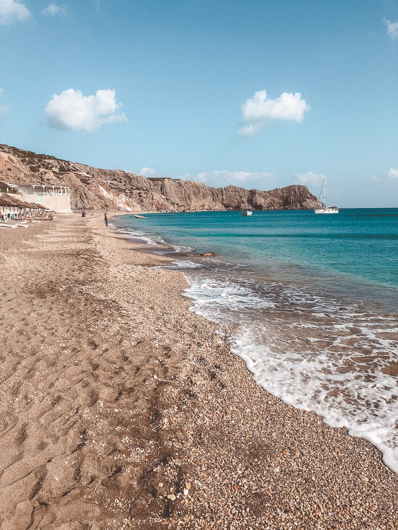 People enjoying the  crystal clear waters, rocky cliffs and and pebbly beach of Paralia Paleochori on Milos when Greek Island Hopping