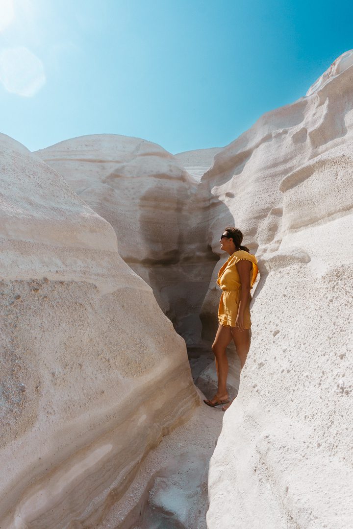 A girl in a yellow romper explores the moon-like surface of Sarakiniko Beach on Milos Island in Greece. 