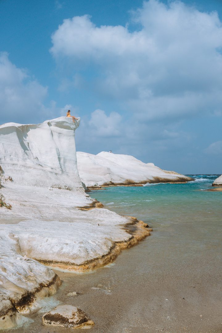 A girl sits atop an oceanside cliff of Sarakiniko Beach; a must see on Milos Island in Greece. 