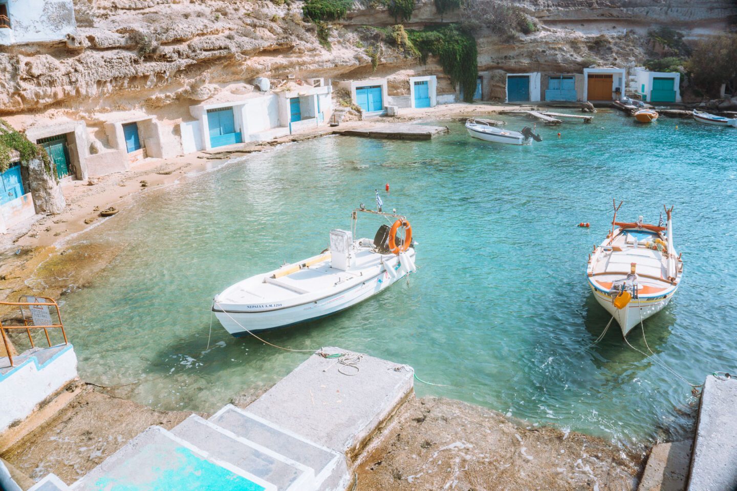 On this Milos travel guide you must visit Mandrakia, a tiny fishing village with colourful boathouses.