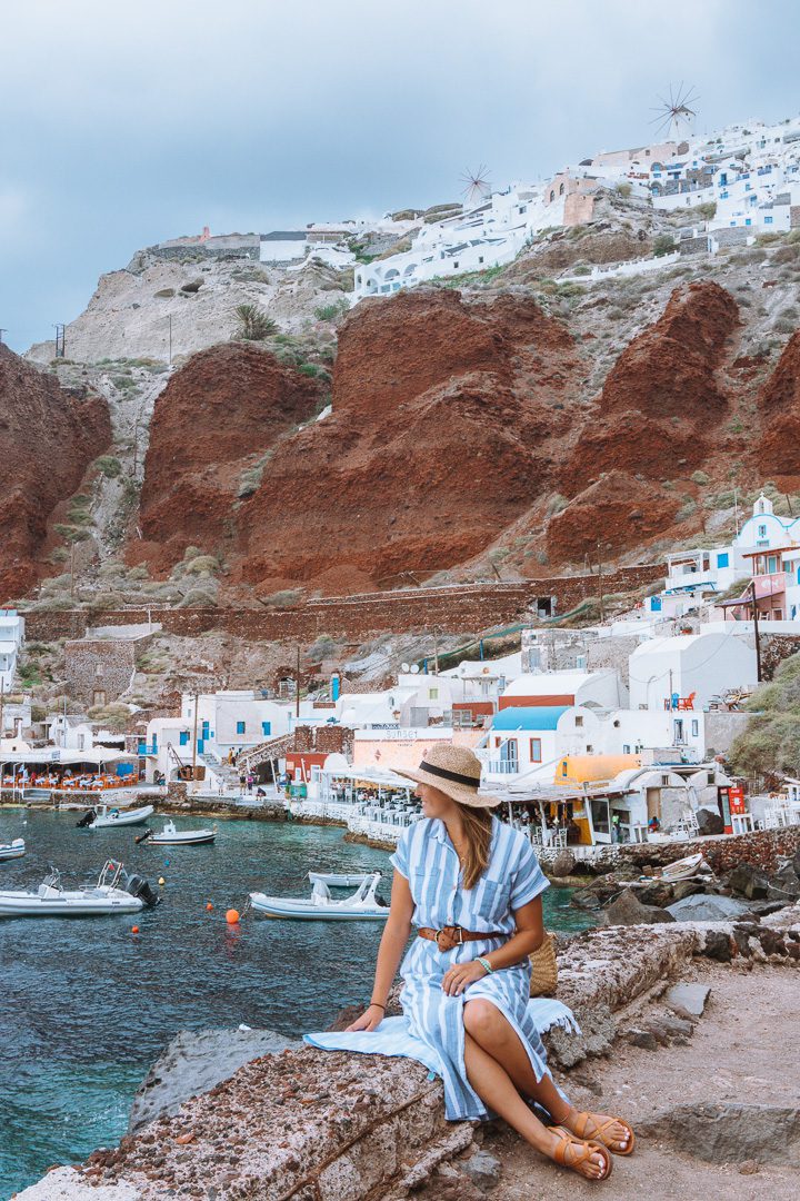 A girl sits and admires the beautiful views from Ammoudi Bay on Santorini Island in Greece